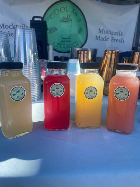 Four bottles of batched Cool as a Cucumber mocktails lined up on an event bar top