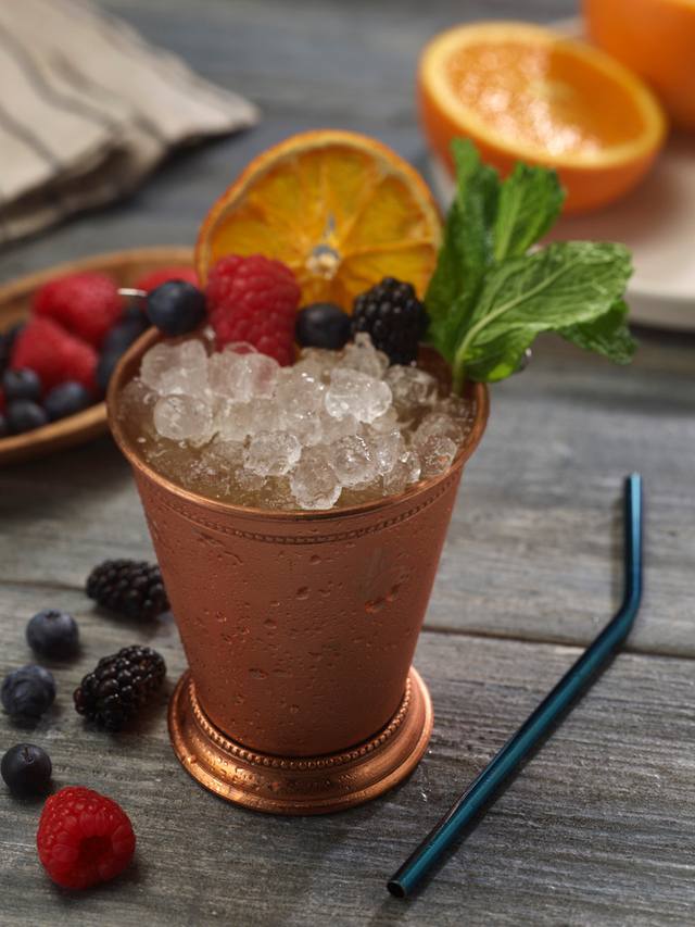 Copper julep cup packed with crushed ice, berries, dehydrated orange and fresh mint