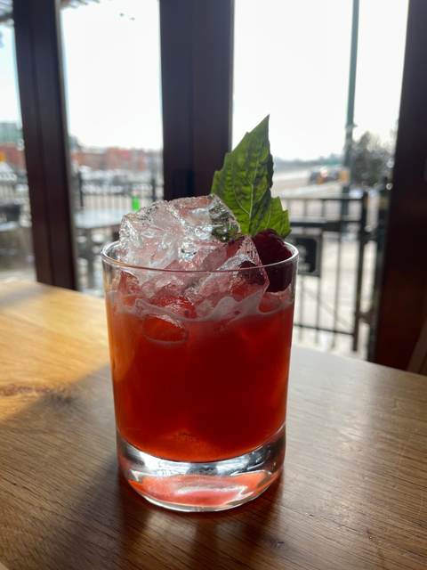 Citizens Brigade whiskey cocktail over crushed ice with a raspberry and basil leaf