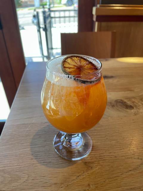 Dark n Stormy in a footed glass with a dehydrated lime wheel on a bar top