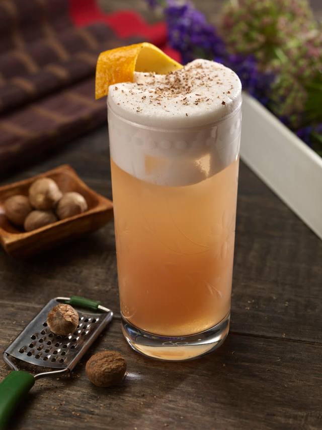 Etched highball of a creamy flip topped with freshly grated nutmeg and lemon peel
