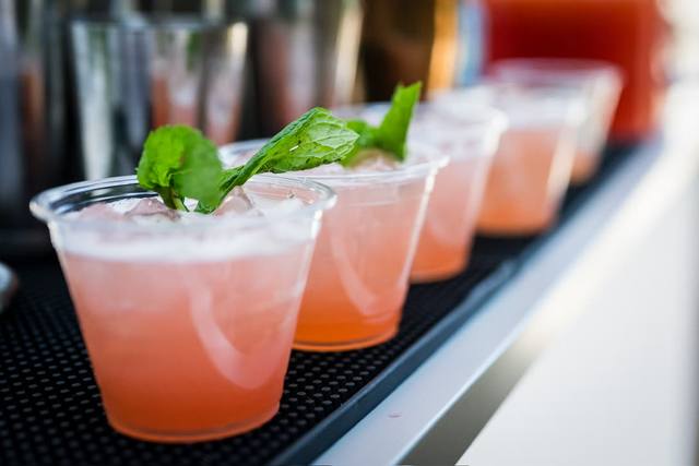 A row of grapefruit spritz cocktails garnished with fresh mint on a bar service mat
