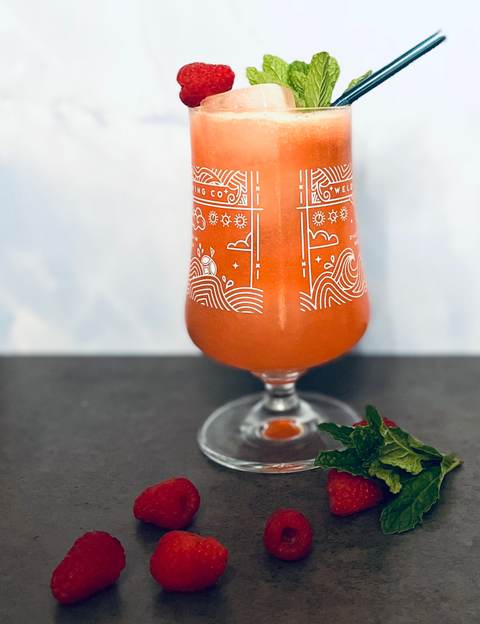 Frozen raspberry mocktail in a stemmed glass with mint and fresh raspberries
