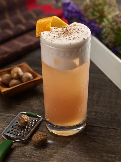 Sloe Gin Fizz in a tall glass topped with freshly grated nutmeg and citrus peel