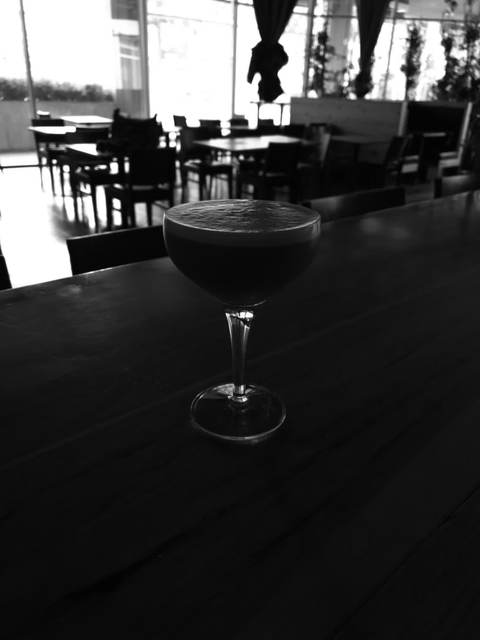 Smoked whiskey sour with a foam cap served on a bar top