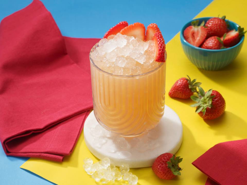 Fluted glass of strawberry crush topped with pebble ice and fresh strawberry slices