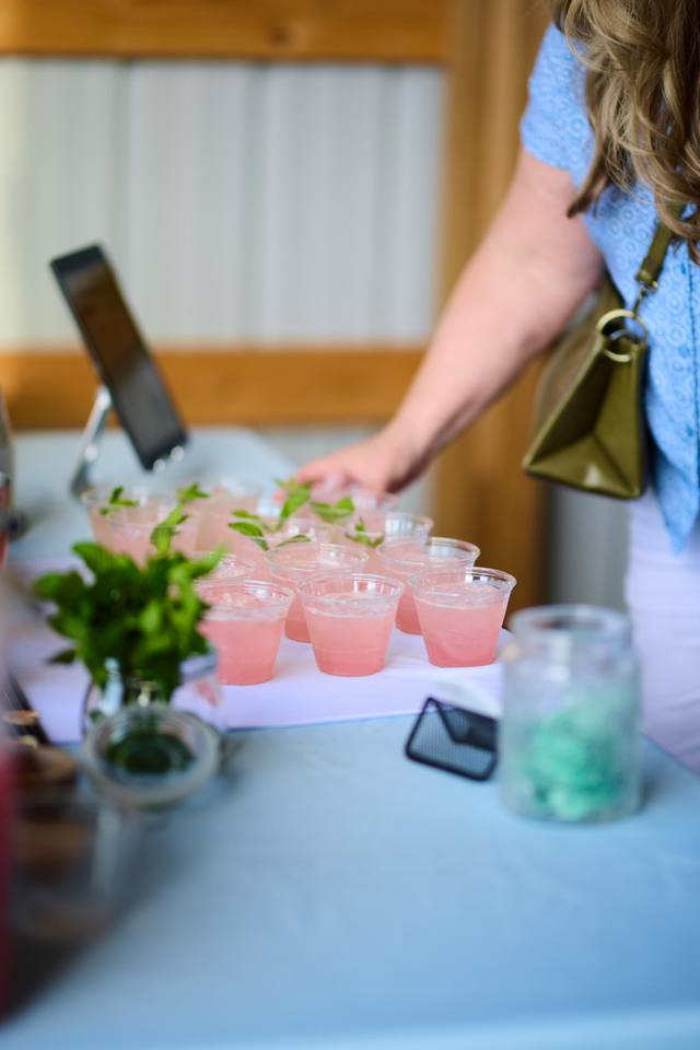Guest taking a pink welcome cocktail from a tray of mint garnished cups