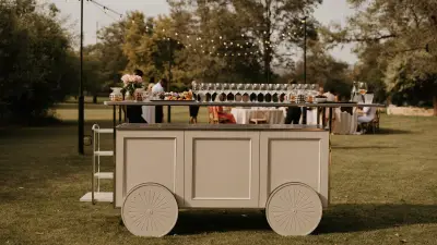 Mobile bar set up on a lawn under string lights at a backyard wedding