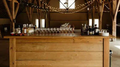 Rustic bar set up inside a barn venue with warm string lighting