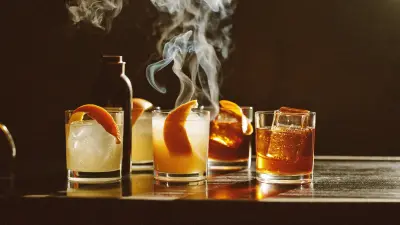 Amber spirit-forward cocktails with orange peel on a bar in warm autumn light