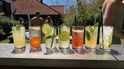 Frozen and citrus cocktails lined up on an outdoor bar in bright summer sun