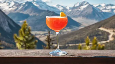 Bright citrus cocktail on a bar rail with mountain scenery behind it