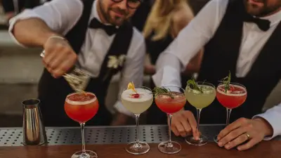 Bartenders lining up finished cocktails on a bar during wedding cocktail hour