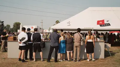 Festival bar tent with several bartenders serving a long line of guests outdoors